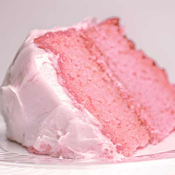 A slice of Mikki's Soul Food Cafe's pink strawberry cake with light pink frosting.
