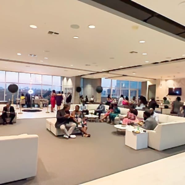 Guests socialize in a modern, spacious lounge with white sofas and large windows.