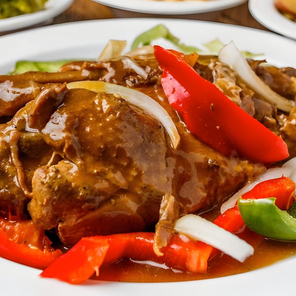 Mikki's Soul Food Cafe's smothered chicken with gravy, red and green bell peppers, and onions.