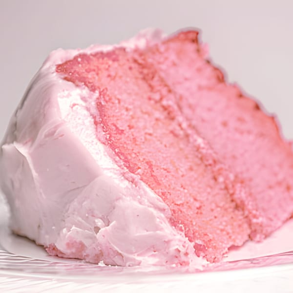 A slice of Mikki's Soul Food Cafe's pink strawberry cake with light pink frosting.