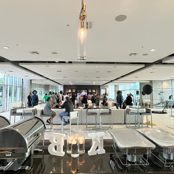 Modern event space with guests mingling, a buffet, and decorative 'B' and 'K' letters.
