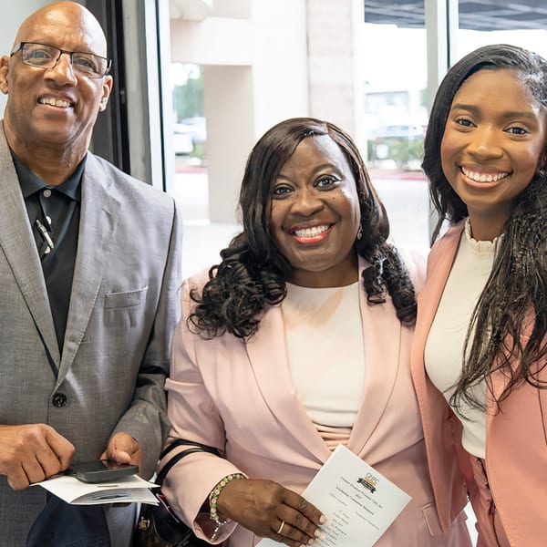 Three smiling people, two women and one man, formally dressed at a GHFC Scholarship event.
