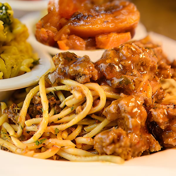 A plate of Mikki's Soul Food Cafe's spaghetti and meatballs, candied yams, and macaroni.