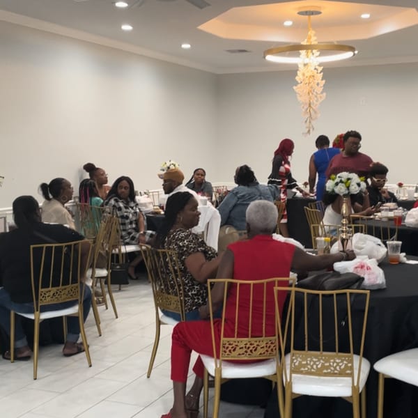 Guests seated at black-draped tables with gold chairs under a modern chandelier at Mikki's Soul Food Cafe.