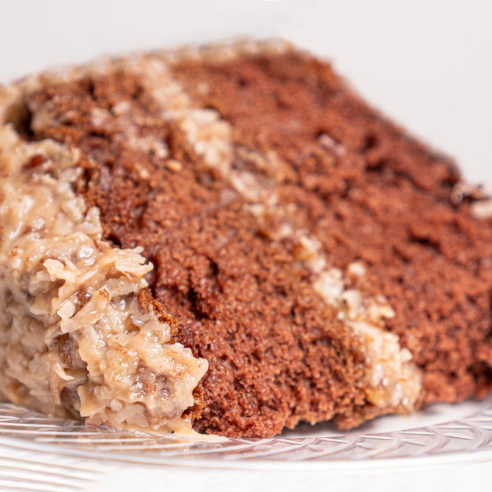 Close-up of a crumb-coated chocolate dessert with creamy filling on a patterned white plate.