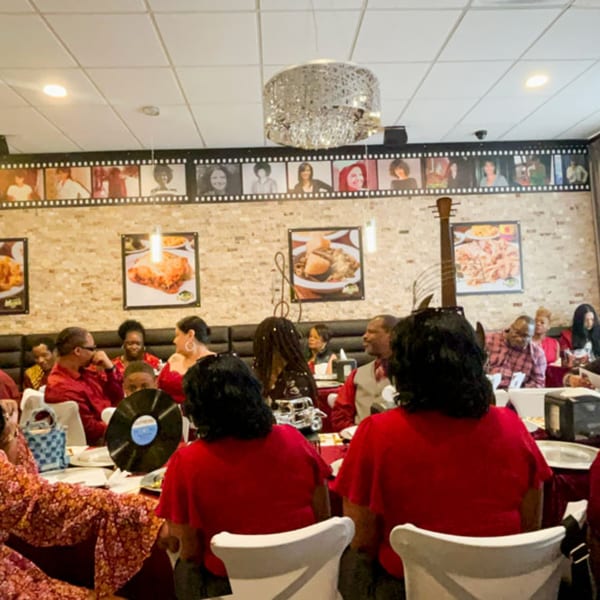 Diners in red shirts enjoying a meal at Mikki's Soul Food Cafe, with food posters and film strip decor.