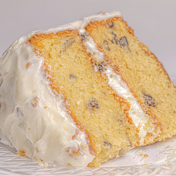 A slice of Mikki's Soul Food Cafe's yellow cake with white frosting and nuts.