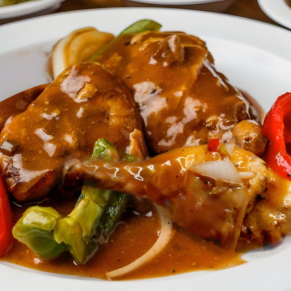 Mikki's Soul Food Cafe's smothered chicken with gravy, green and red bell peppers, and onions.